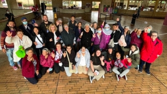 Grupo de personas adultas mayores con jóvenes en la biblioteca posando para la foto y sonriendo