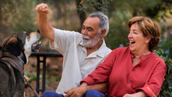 Pareja de abuelos felices jugando con su perro.