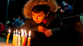 Foto de velitas encendidas y de fondo las manos de un niño