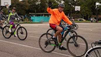 Adultos mayores montando bicicleta sonriendo y saludando