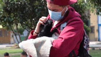 Colaborador del Instituto Distrital de Protección y Bienestar Animal con un perrito en sus manos consintiéndolo