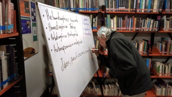 Señora de la tercera edad participando activa en el taller escribiendo sobre el tablero