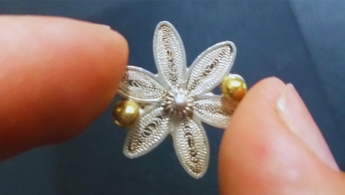 imagen de mano sosteniendo flor hecha en filigrana