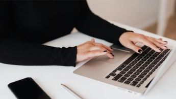 mujer escribiendo en un computador