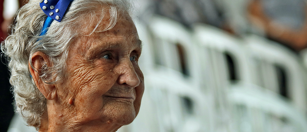 Señora de la tercera edad mirando hacia la derecha y con un gesto de sonrisa.