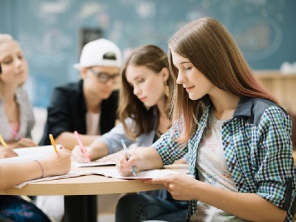 cuatro personas jóvenes reunidas tomando nota