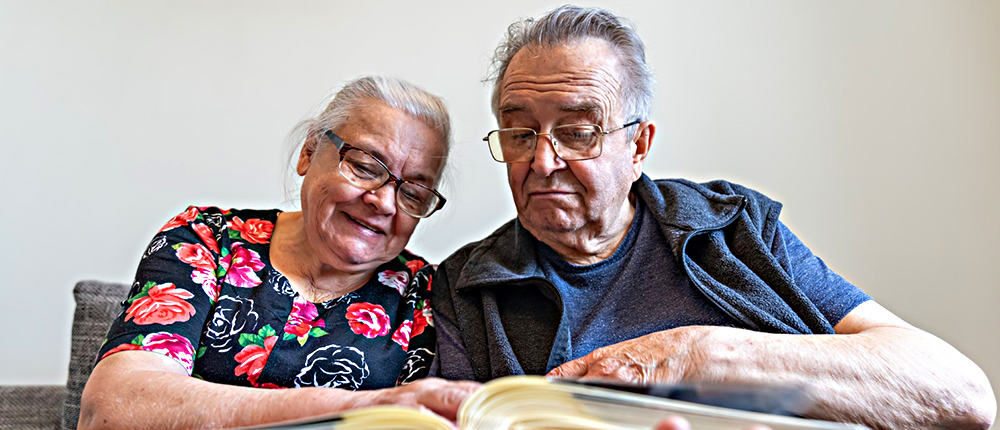 En la foto se ven dos personas de la tercera edad, hombre y mujer sonriendo y apreciando un libro con tranquilidad - Foto de jubilados creado por pvproductions - www.freepik.es