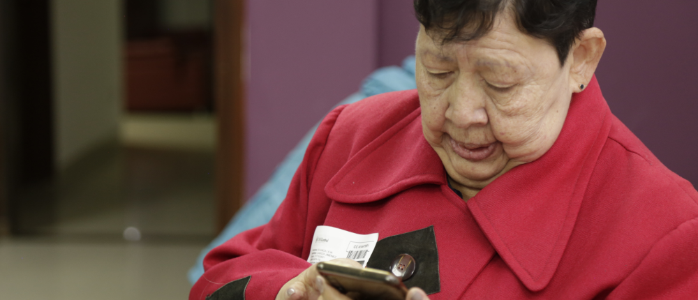Señora de la tercera edad manipulando un teléfono celular