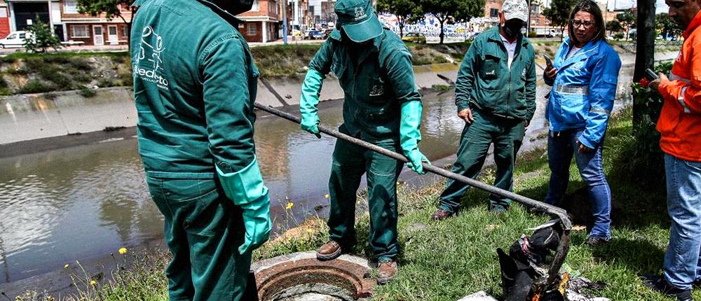 Colaboradores de la EAAB realizando limpieza a una alcantarilla.